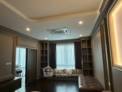 Luxurious living room with elegant dark wood flooring and built-in shelving, featuring cozy seating by the window.