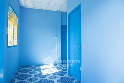 Vibrant blue hallway with patterned tile flooring and bright natural light.