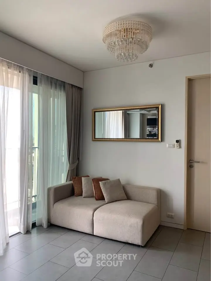 Modern living room with elegant chandelier and cozy sofa near balcony.