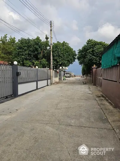 Quiet residential street with gated homes and lush greenery