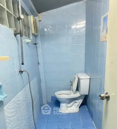 Compact blue-tiled bathroom with shower and toilet, ideal for small spaces.