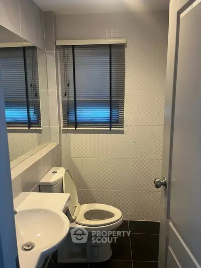 Modern bathroom with sleek fixtures and neutral tiles, featuring a compact design for efficient space use.