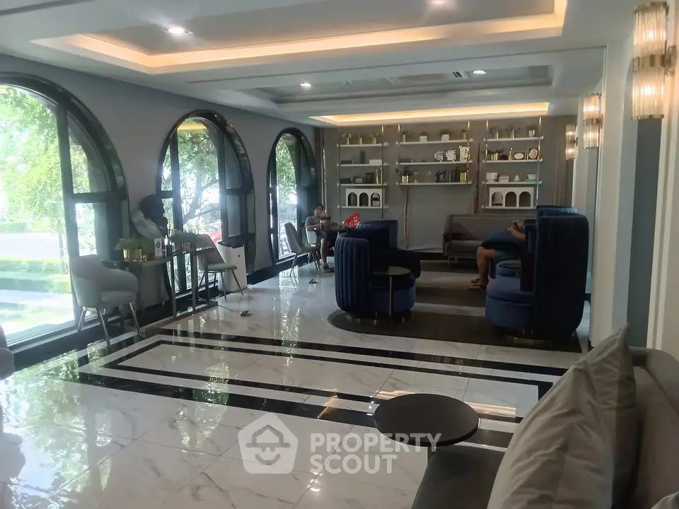 Luxurious modern living room with elegant decor and large arched windows overlooking lush greenery.
