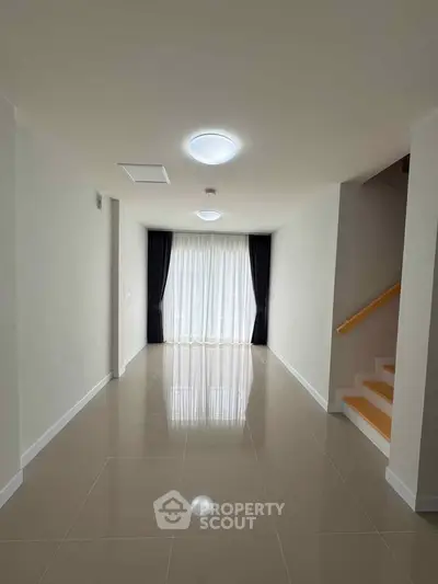 Spacious modern living room with glossy tiled floors and large window for natural light.
