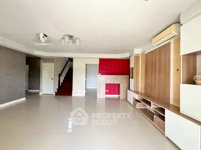 Spacious living room with modern built-in cabinets and air conditioning, ideal for family gatherings.