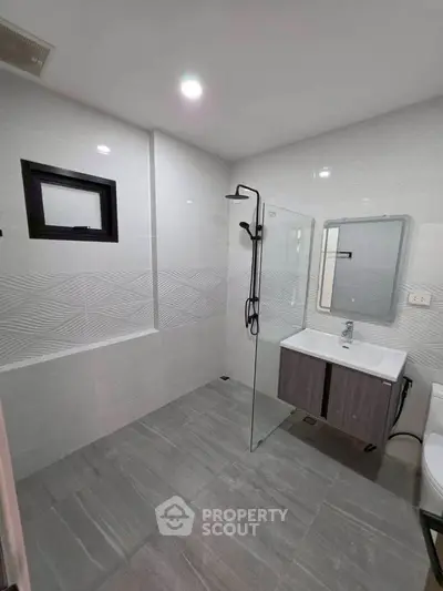 Modern bathroom with sleek design, featuring a glass shower partition and stylish vanity.