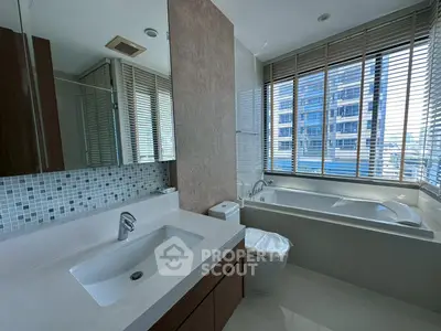 Luxurious bathroom with modern fixtures and large window view in high-rise apartment.