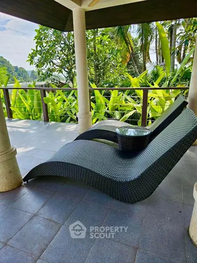 Luxurious balcony with stylish wicker loungers and lush tropical garden view