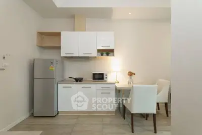 Modern kitchen with sleek white cabinets and dining area in a cozy apartment.