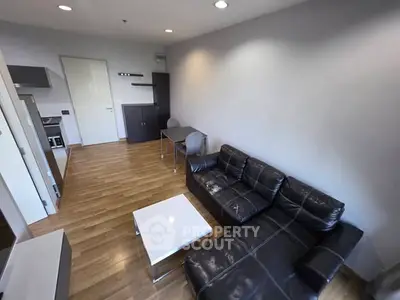 Modern living room with sleek black leather sofa and wooden flooring