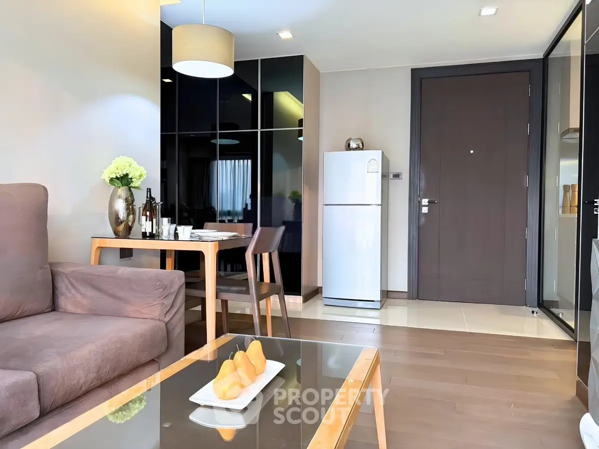 Modern living room with sleek furniture and dining area, featuring a stylish glass coffee table and cozy seating.