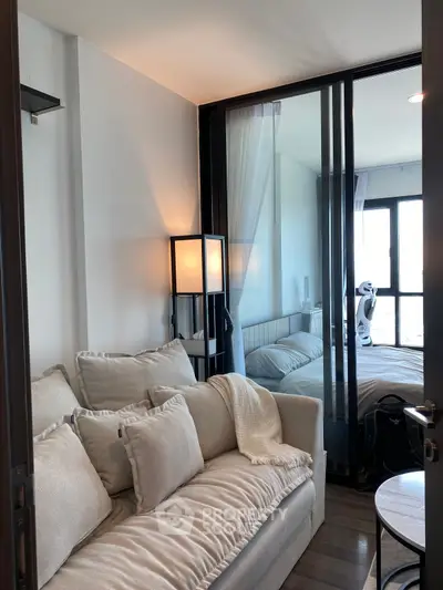 Modern living room with cozy sofa and glass partition leading to bedroom