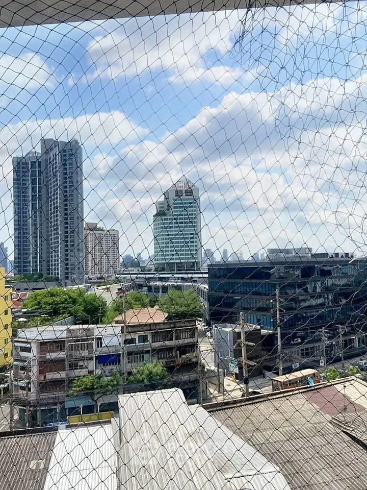 Stunning cityscape view from a high-rise building balcony with protective netting.