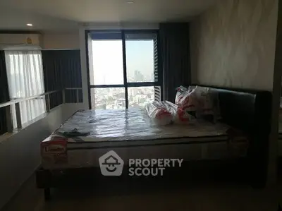 Modern bedroom with city view and large window, featuring a new mattress and stylish decor.