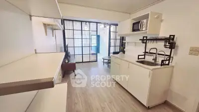 Modern studio apartment with open kitchen and stylish living area, featuring sleek cabinetry and natural light.