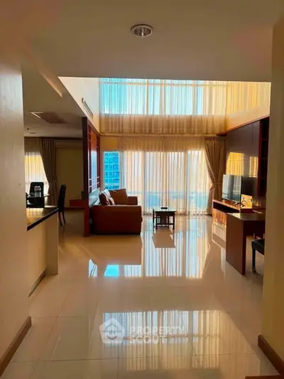 Spacious living room with high ceilings and large windows offering abundant natural light.