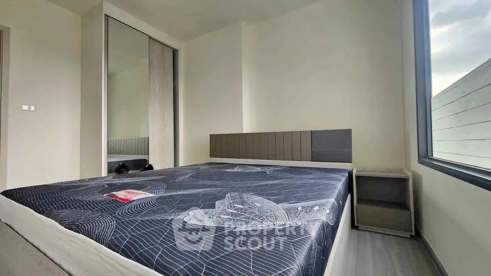 Modern bedroom with large window and stylish decor in a contemporary apartment.