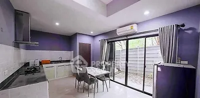 Modern kitchen with open layout, sleek appliances, and large sliding glass doors to outdoor area.