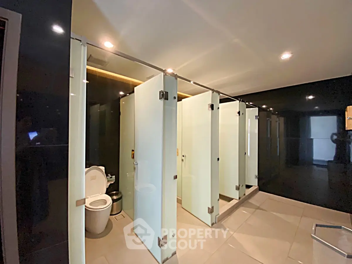 Modern public restroom with sleek glass partitions and contemporary design.