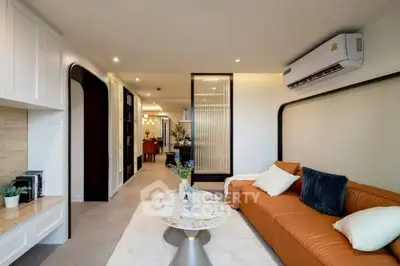 Modern living room with stylish furniture and open layout, featuring a cozy orange sofa and elegant decor.