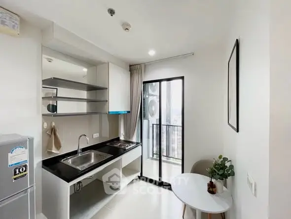 Modern kitchen with sleek design and balcony view in a high-rise apartment.