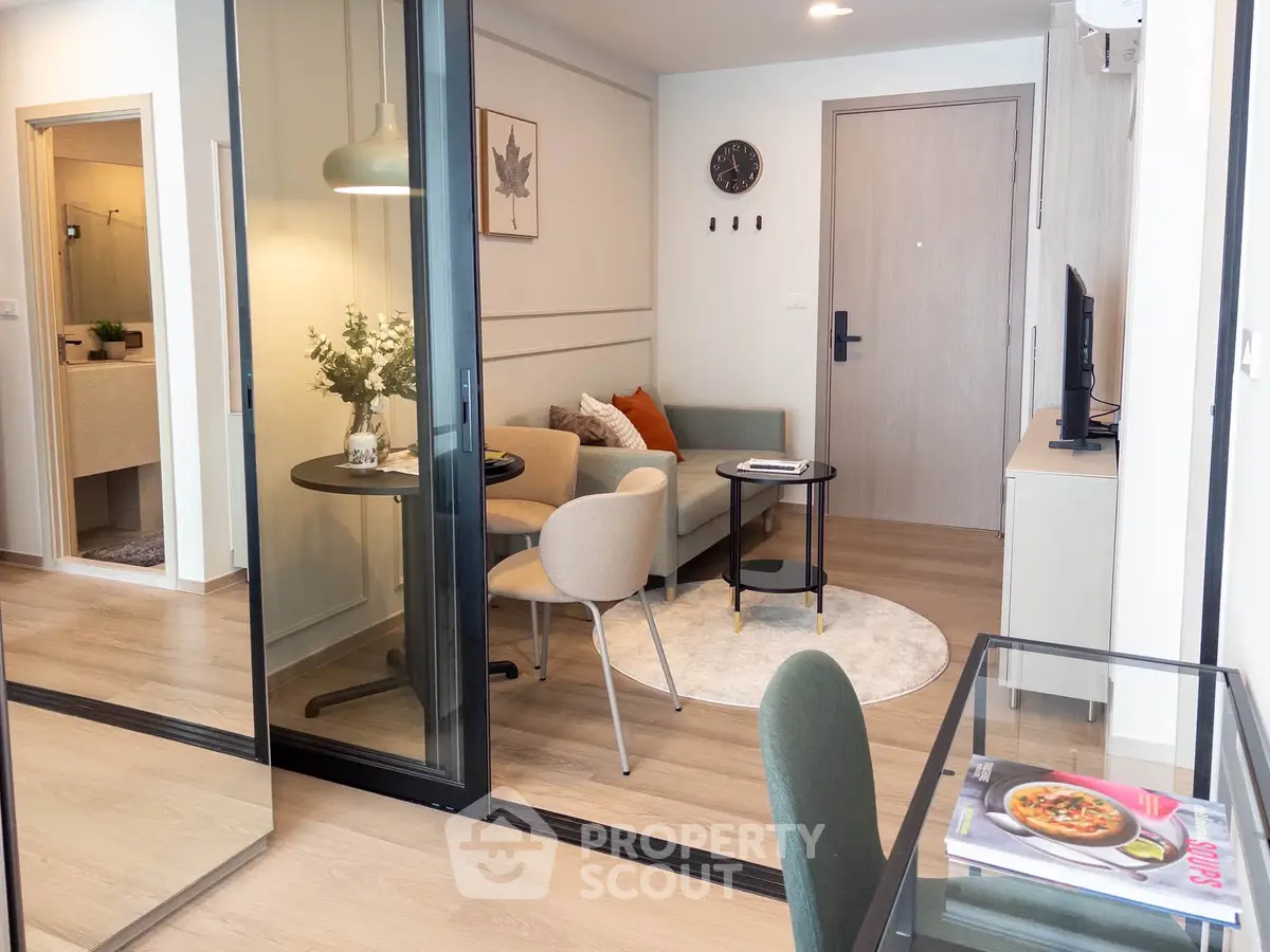 Modern living room with glass partition, cozy seating, and stylish decor in a contemporary apartment.