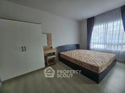 Spacious bedroom with modern furniture and large window for natural light.