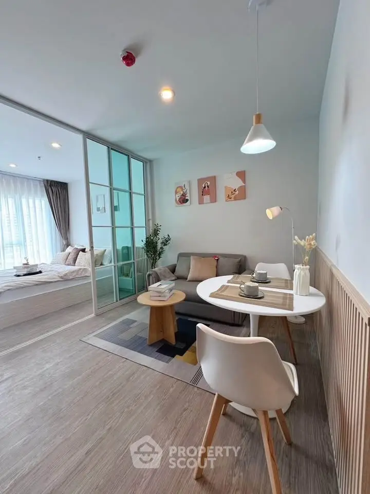 Modern living room with cozy decor and adjacent bedroom in open layout apartment.