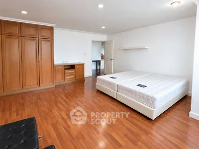 Spacious bedroom with wooden flooring and ample storage space