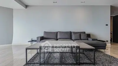 Modern living room with sleek gray sofa and stylish coffee table on textured rug.