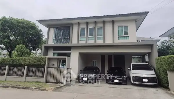 Modern two-story house with spacious driveway and three parked cars