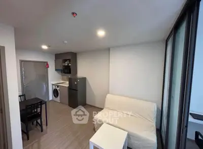 Modern apartment interior with compact living room and kitchen featuring washing machine and dining area.