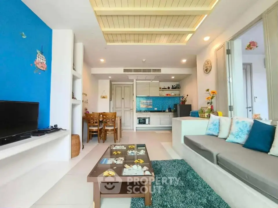 Charming living room with modern decor and vibrant blue accents, open layout leading to a cozy dining area.