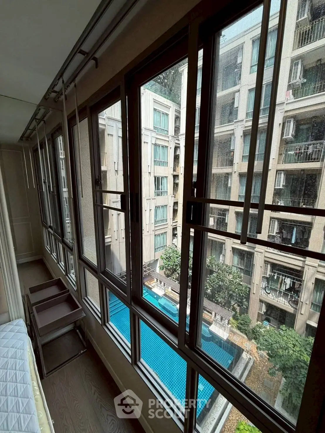 Spacious apartment with large windows overlooking a serene pool and modern building view.
