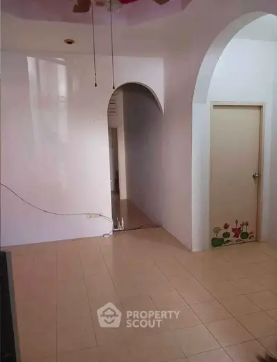 Spacious interior with tiled flooring and arched doorways, ideal for customization.