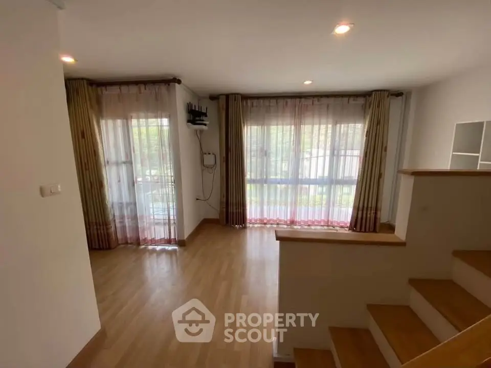 Spacious living room with large windows and wooden flooring, perfect for natural light.