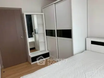 Modern bedroom with sleek wardrobe and mirror, showcasing minimalist design and ample storage space.