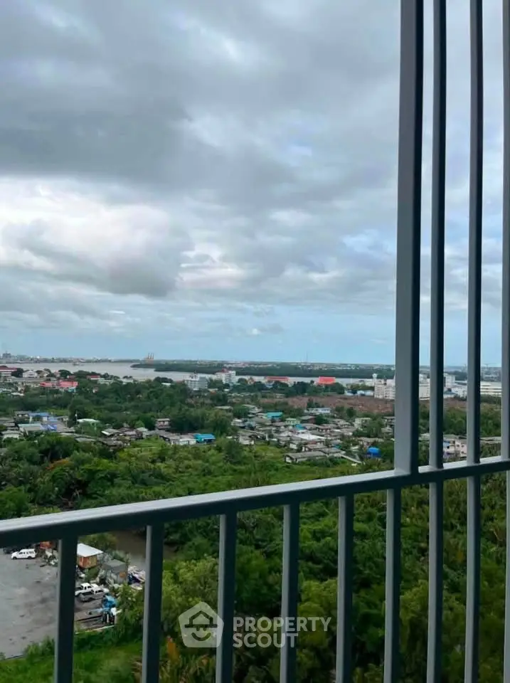 Stunning high-rise balcony view overlooking lush greenery and distant cityscape under a cloudy sky.