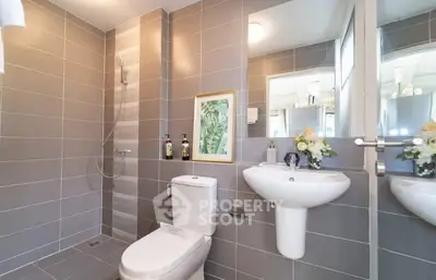 Modern bathroom with sleek gray tiles and elegant fixtures, featuring a shower and stylish decor.