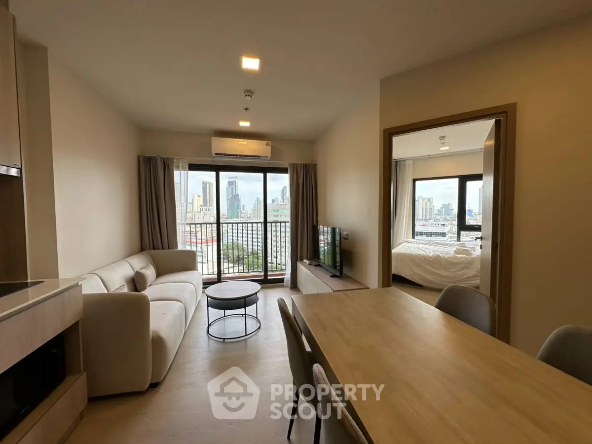 Modern apartment with open living room and city view, featuring a cozy dining area and natural light.