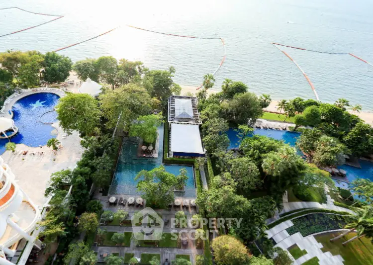Stunning aerial view of luxury beachfront property with lush gardens and multiple pools.