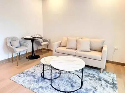 Modern living room with cozy sofa and stylish coffee tables on a plush rug.