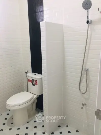 Modern bathroom with white tiles, shower, and toilet in a sleek design.