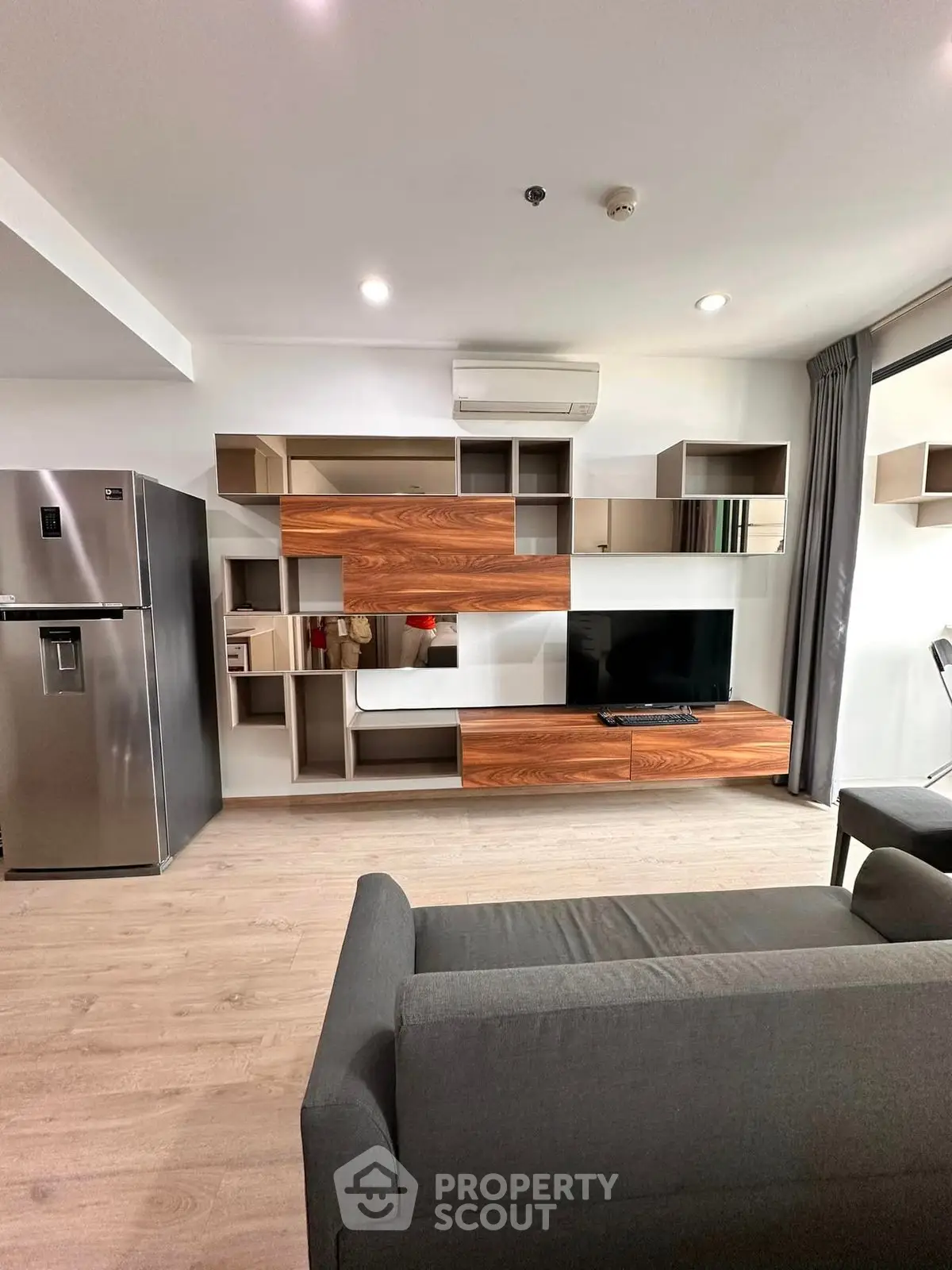 Modern living room with sleek furniture and stainless steel fridge, perfect for contemporary living.