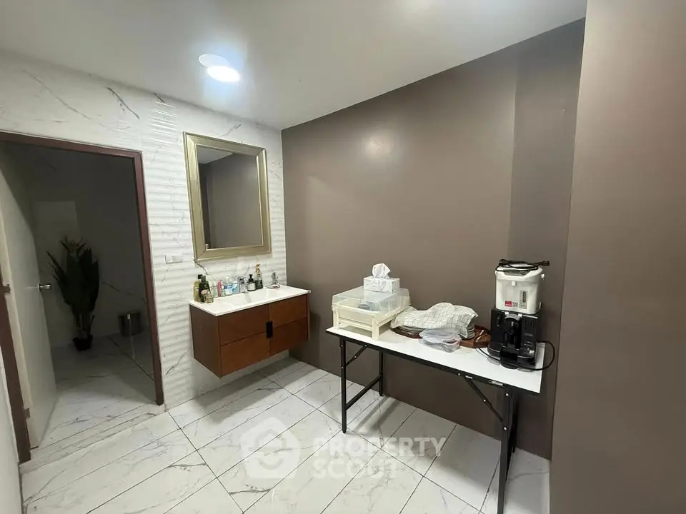 Modern bathroom with sleek vanity and coffee station, featuring elegant tile flooring and neutral wall tones.