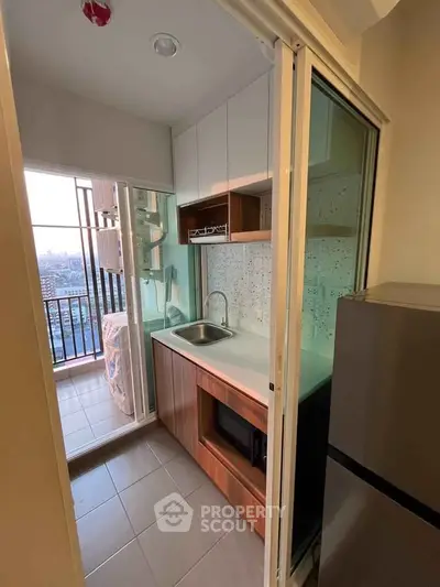 Compact kitchen with balcony view, modern appliances, and sleek cabinetry in urban apartment.