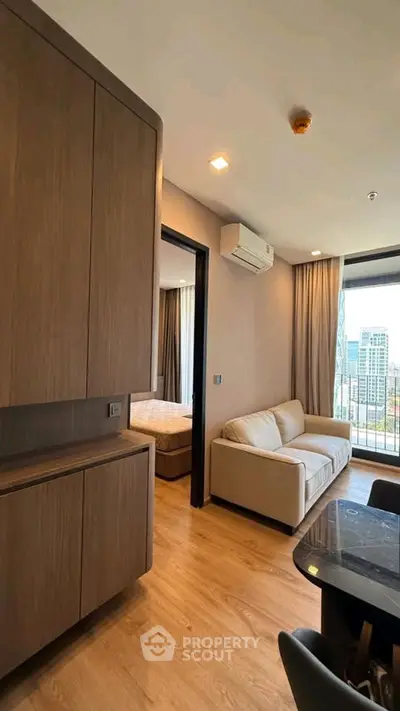 Modern apartment interior with wooden flooring and city view from balcony.