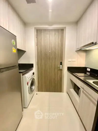 Modern kitchen with sleek appliances and compact design, featuring a washing machine and ample storage.