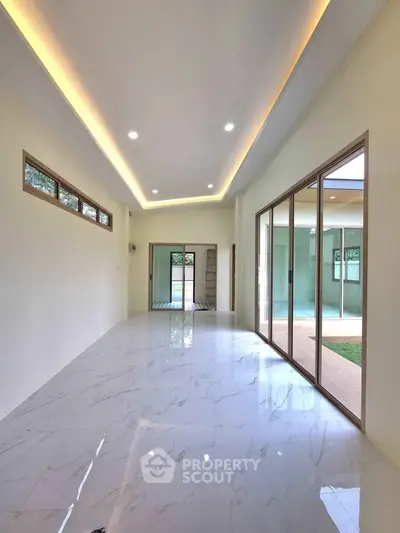 Spacious modern living room with marble flooring and large sliding glass doors.