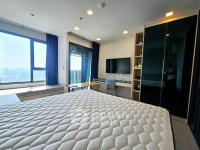 Modern bedroom with large window and city view, featuring a comfortable bed and sleek furniture.